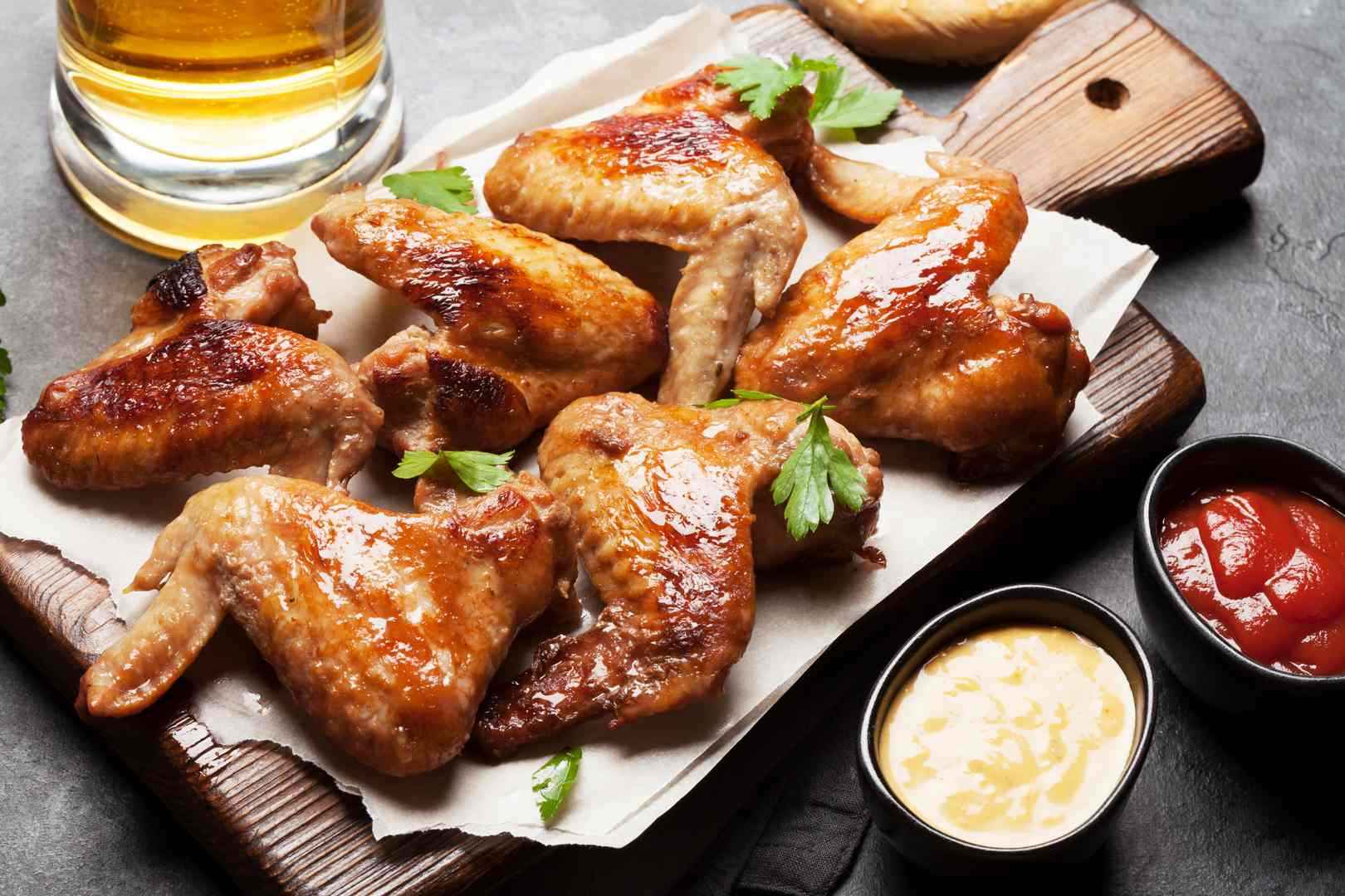 Hot barbecue chicken wings with sauce and draft beer.